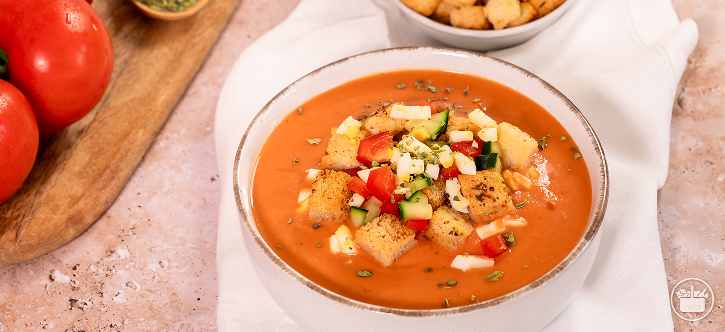 Gaspacho refrescante servido numa tigela com ingredientes frescos a acompanhar, a sopa ideal.